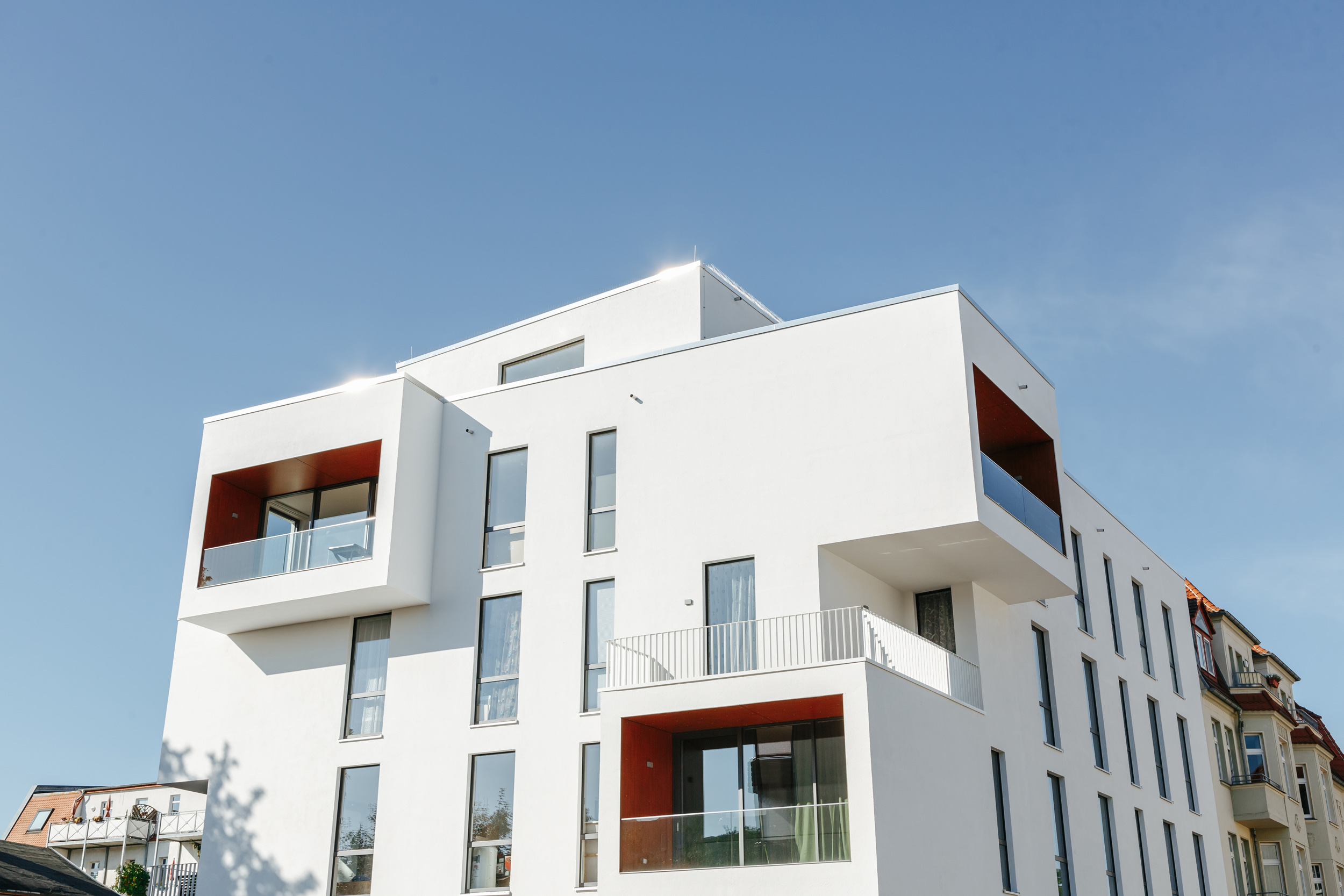 Modernes Mehrfamilienhaus mit minimalistischer Architektur und Balkonen in städtischer Lage.