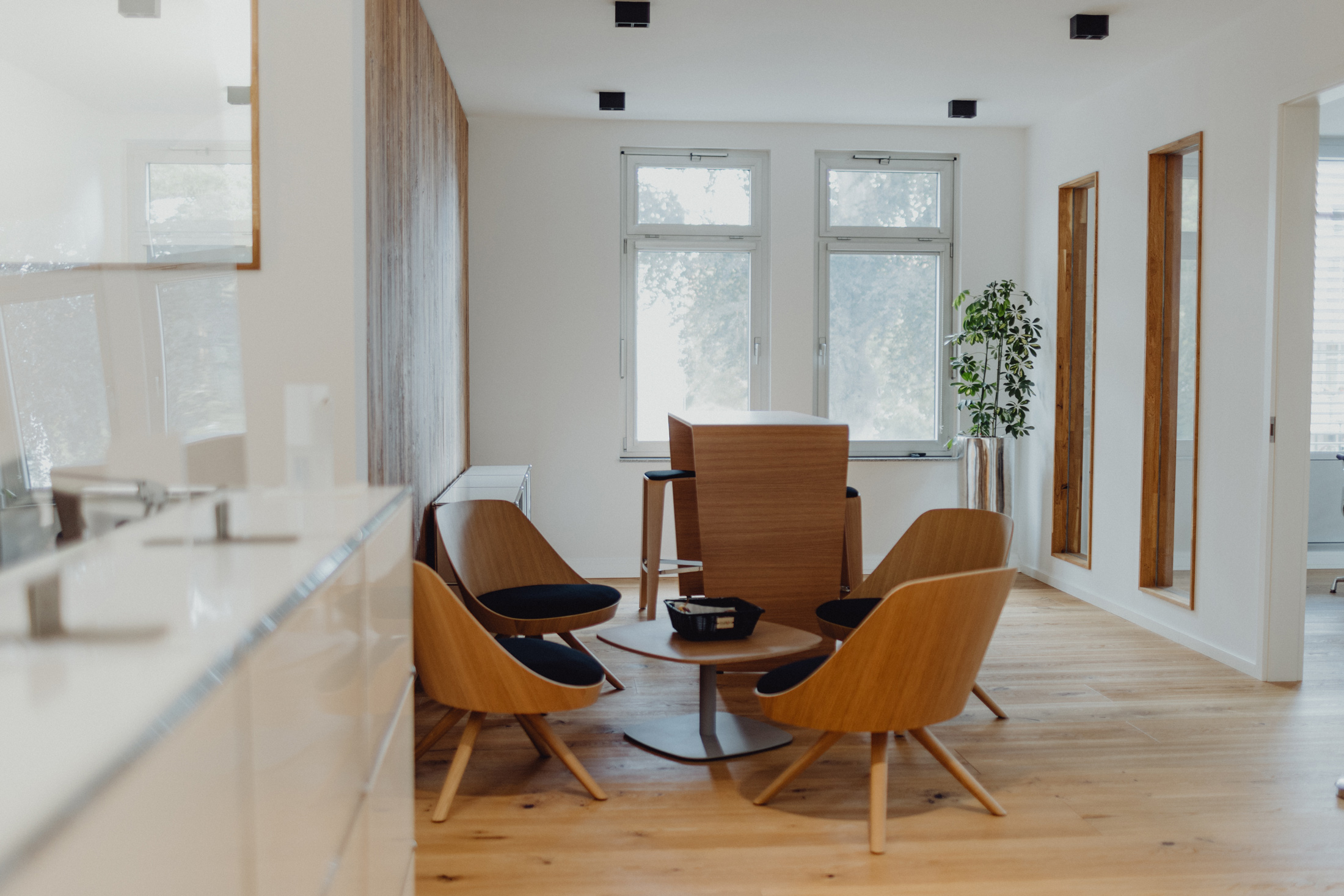 Modern eingerichteter Besprechungsraum mit Holzstühlen, rundem Tisch und viel Tageslicht für eine stilvolle Arbeitsatmosphäre.