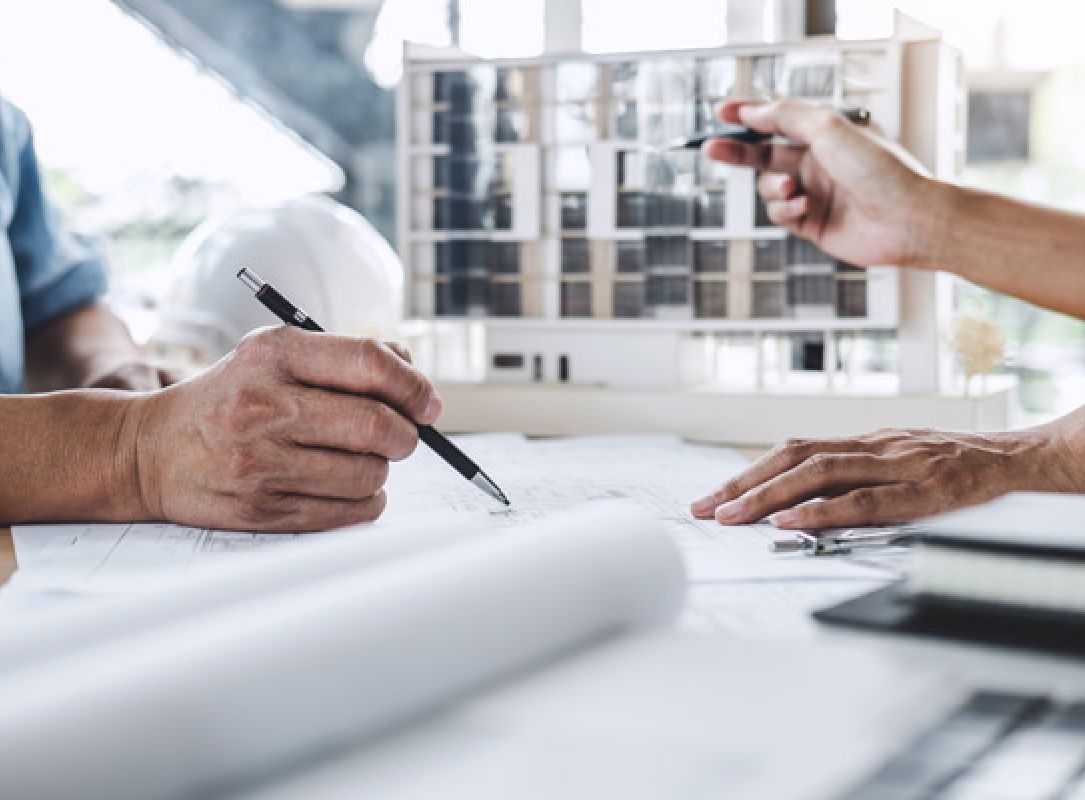 Architekten arbeiten an Bauplänen mit Gebäude-Modell, technische Zeichnungen und Planungskonzept im Fokus.