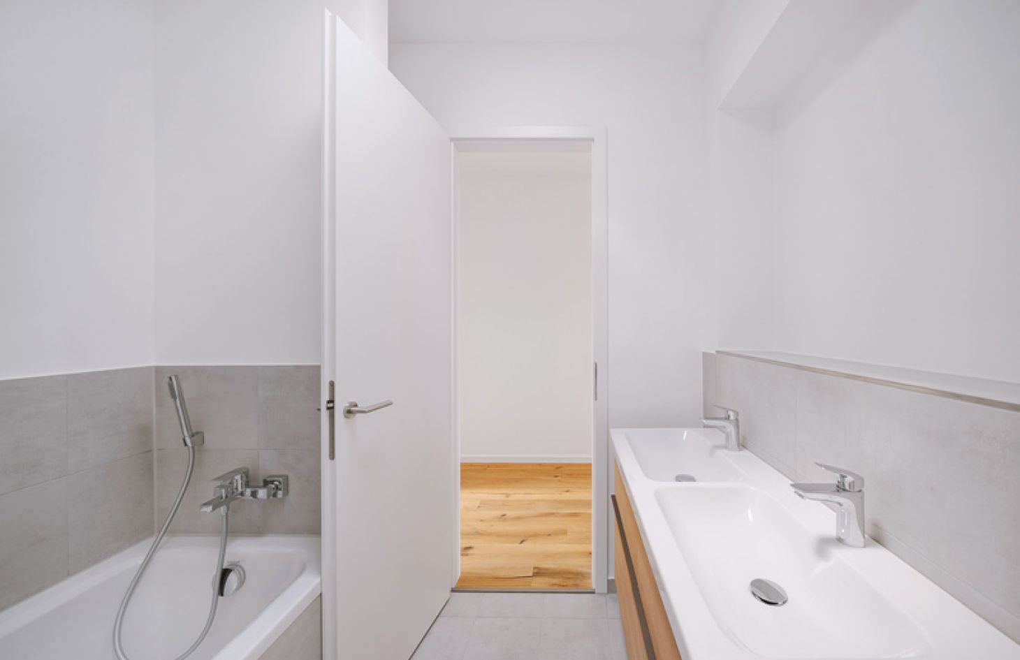Modernes Badezimmer mit Doppelwaschbecken, Badewanne und heller Gestaltung für ein minimalistisches und stilvolles Design.