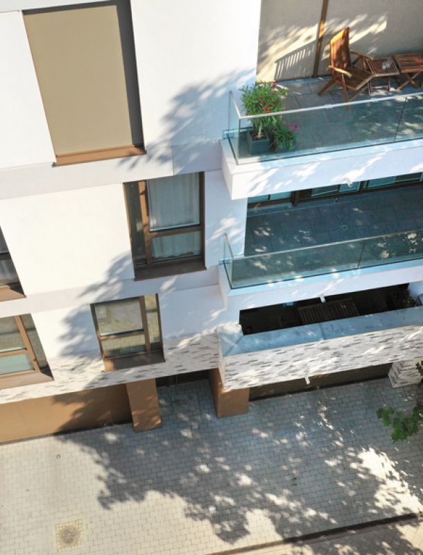 Modernes Wohngebäude mit Glasbalkonen, stilvoller Fassade und grüner Umgebung für urbanes und komfortables Wohnen.