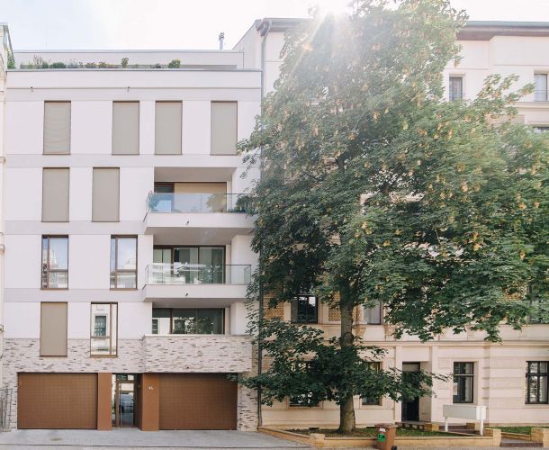 Neues modernes Wohngebäude zwischen traditionellen Altbauten in städtischer Umgebung.