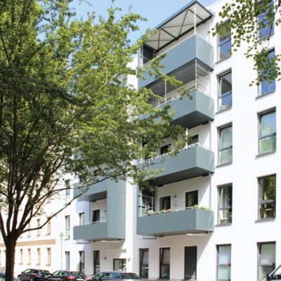 Moderne Wohnanlage mit Balkonen, großen Fenstern und grüner Umgebung in einer ruhigen Stadtlage.