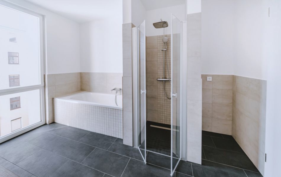 Modernes Badezimmer mit großer Badewanne, begehbarer Dusche und bodentiefem Fenster für helles, offenes Raumgefühl.