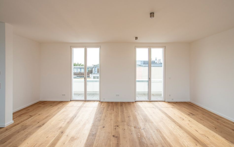 Helles, modernes Wohnzimmer mit Parkettboden, bodentiefen Fenstern und Zugang zum Balkon für ein offenes Wohnkonzept.