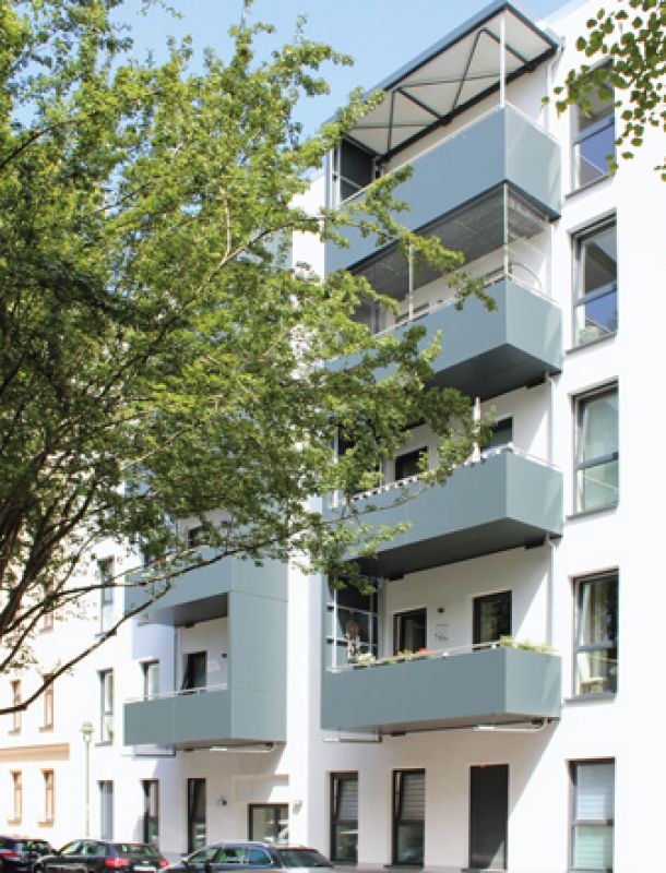 Moderne Wohnanlage mit Balkonen, großen Fenstern und grüner Umgebung in einer ruhigen Stadtlage.