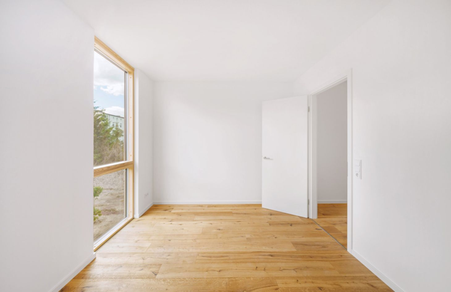 Helles, minimalistisches Zimmer mit Parkettboden, bodentiefem Fenster und weiß gestrichenen Wänden für modernes Wohnen.