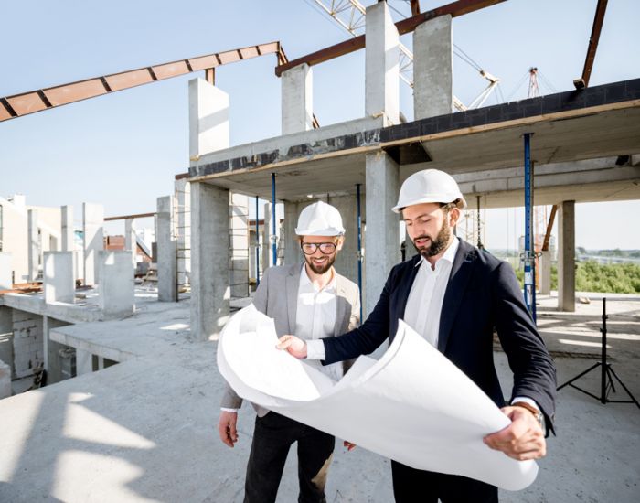 Zwei Ingenieure besprechen Baupläne auf einer aktiven Baustelle.