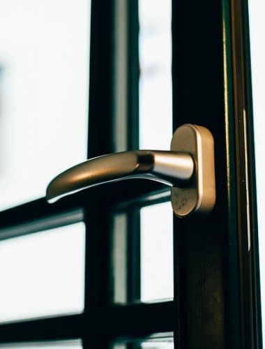 Nahaufnahme eines modernen Türgriffs an einer Glastür mit Sicht auf ein Stadtfenster.