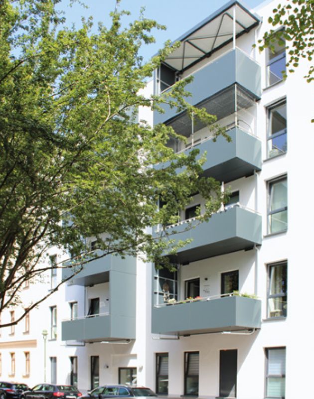 Moderne Wohnanlage mit Balkonen, großen Fenstern und grüner Umgebung in einer ruhigen Stadtlage.