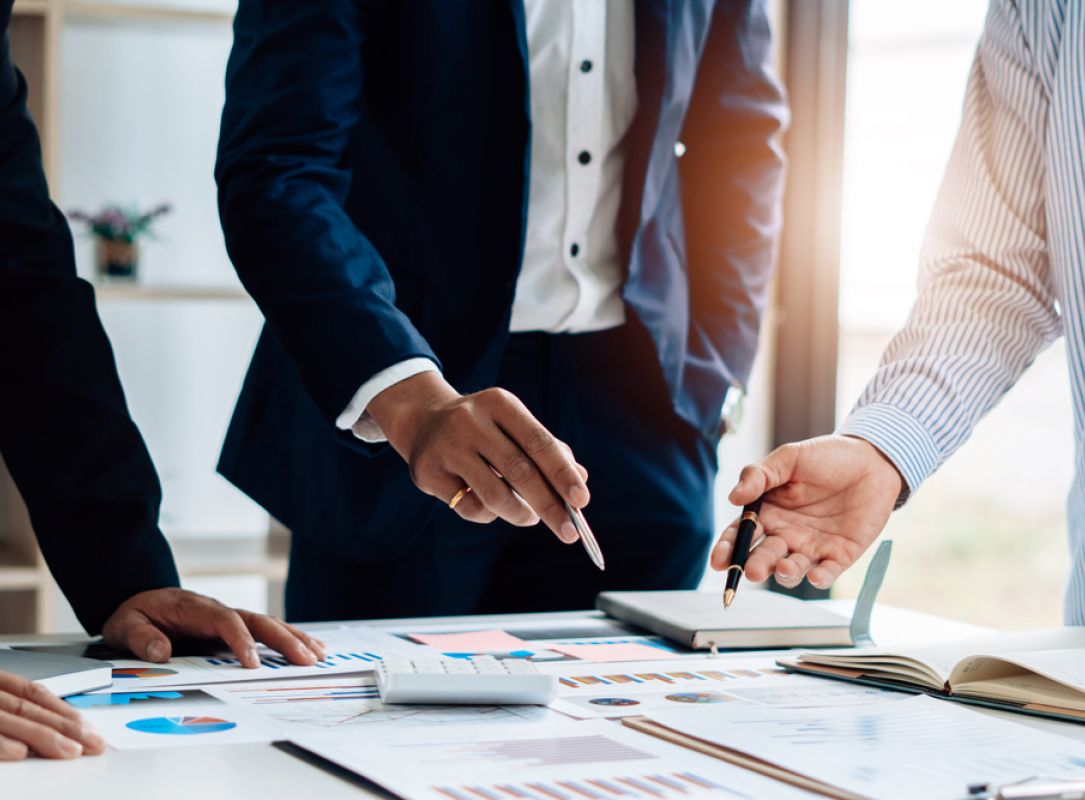 Architekten arbeiten an Bauplänen mit Gebäude-Modell, technische Zeichnungen und Planungskonzept im Fokus.