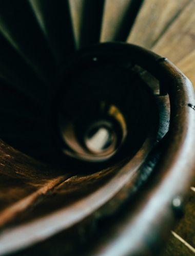 Detailaufnahme einer spiralförmigen Holztreppe mit Fokus auf die Textur und Form.