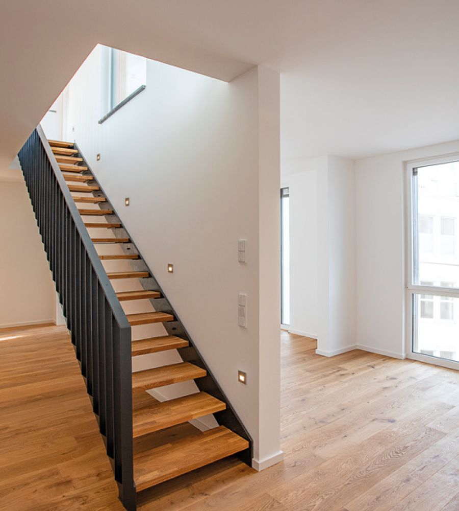 Modernes Hochhaus im Bau mit gelb-blauer Fassade, Baukränen und Arbeitern, aufgenommen bei klarem Himmel.